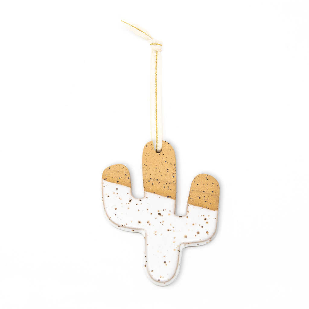 White and tan ceramic cactus ornament with dirt colored speckles. Creme colored ribbon with a gold stripe.