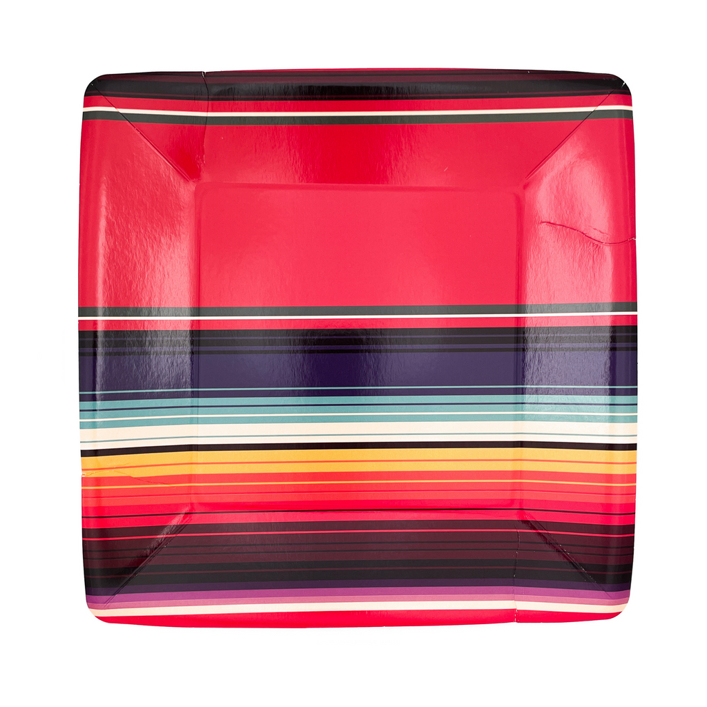 Square, paper dinner plates with red serape print. Colors are blue, red, yellow, white stripes. Small black smudge due to a packing defect